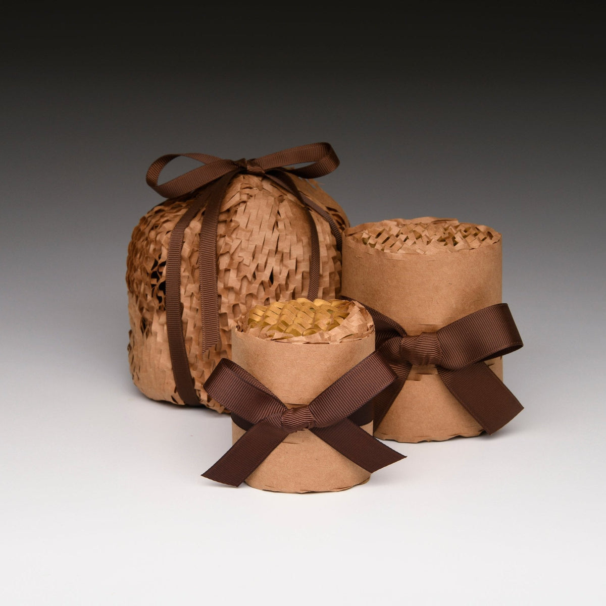 Wrapped candle gift set with woven straw containers and brown ribbon bows.