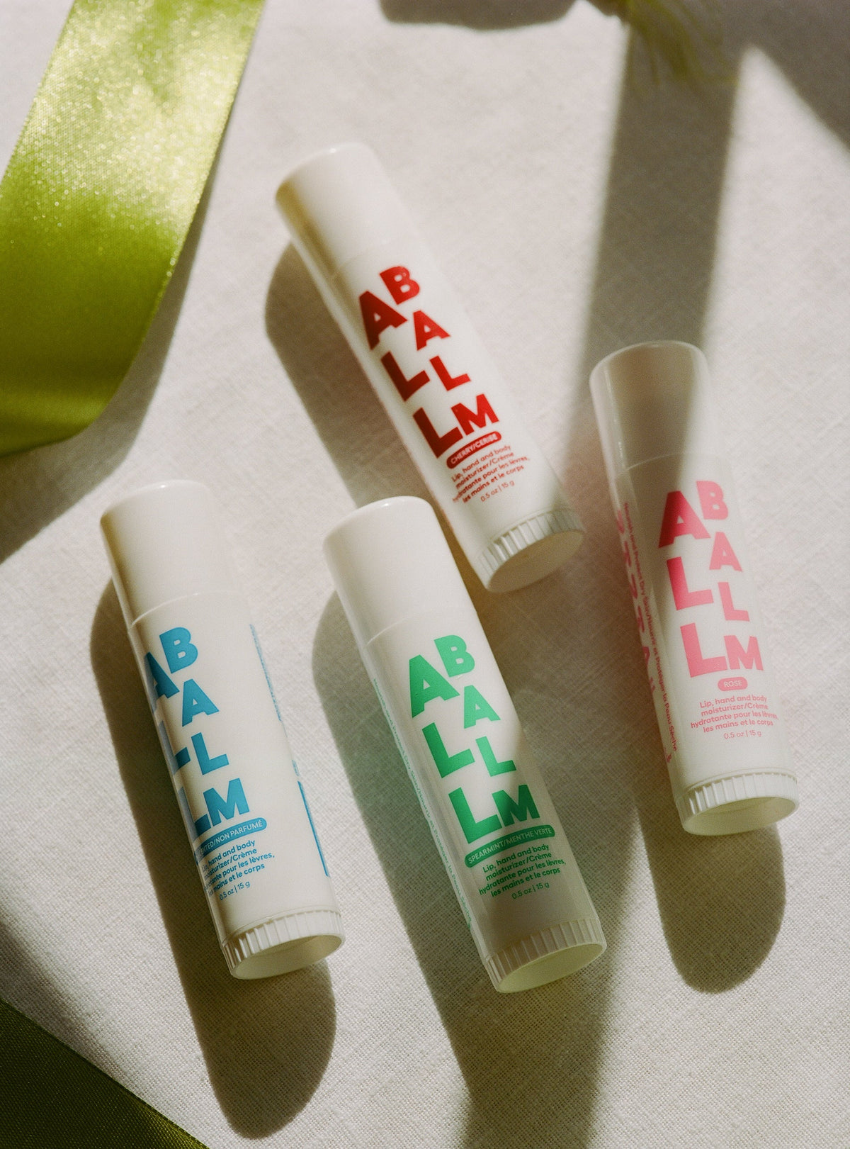 Balm stick tubes on light cloth with colored ABALM scent labels