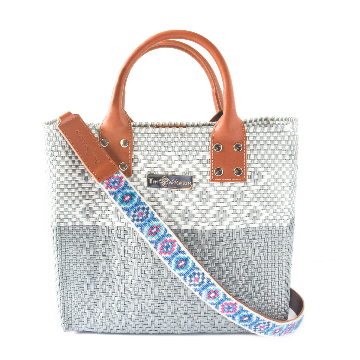 Woven bag strap with blue and pink geometric pattern and tan leather end tabs