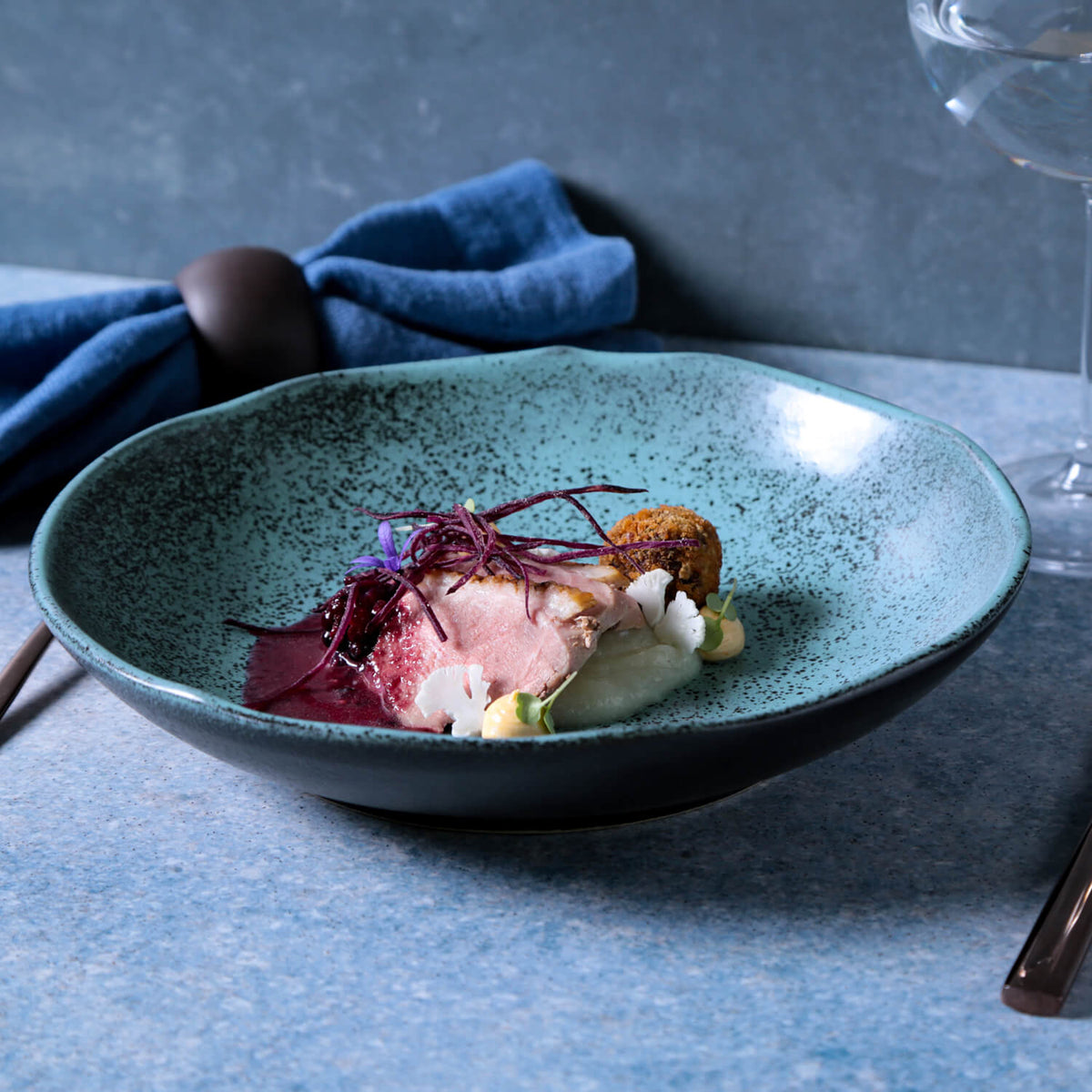 Teal speckled reactive-glaze pasta plate with shallow bowl shape