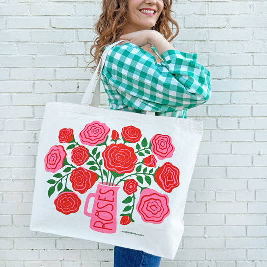 Off-white tote bag with red and pink rose bouquet graphic and pink vase front panel