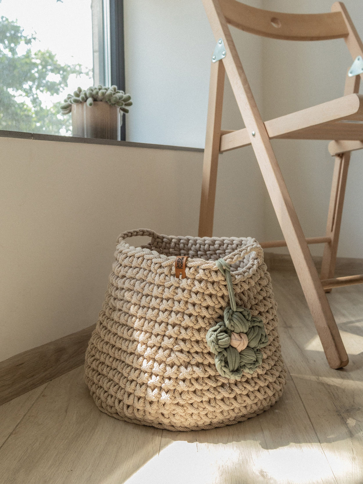 Crochet storage basket in cream with green braided flower and top carry handle