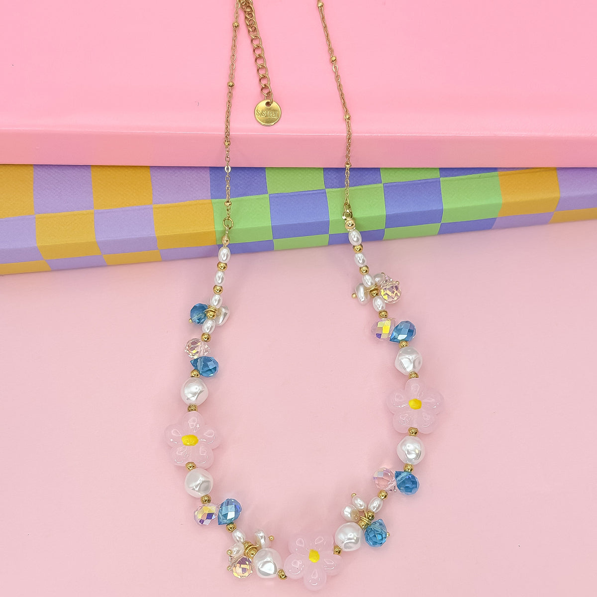 Gold beaded necklace with pink flower charms, yellow centers, pearl and blue crystal beads