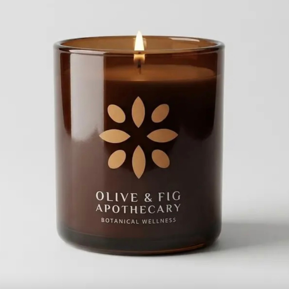 Amber glass jar candle close-up with centered flame and floral emblem