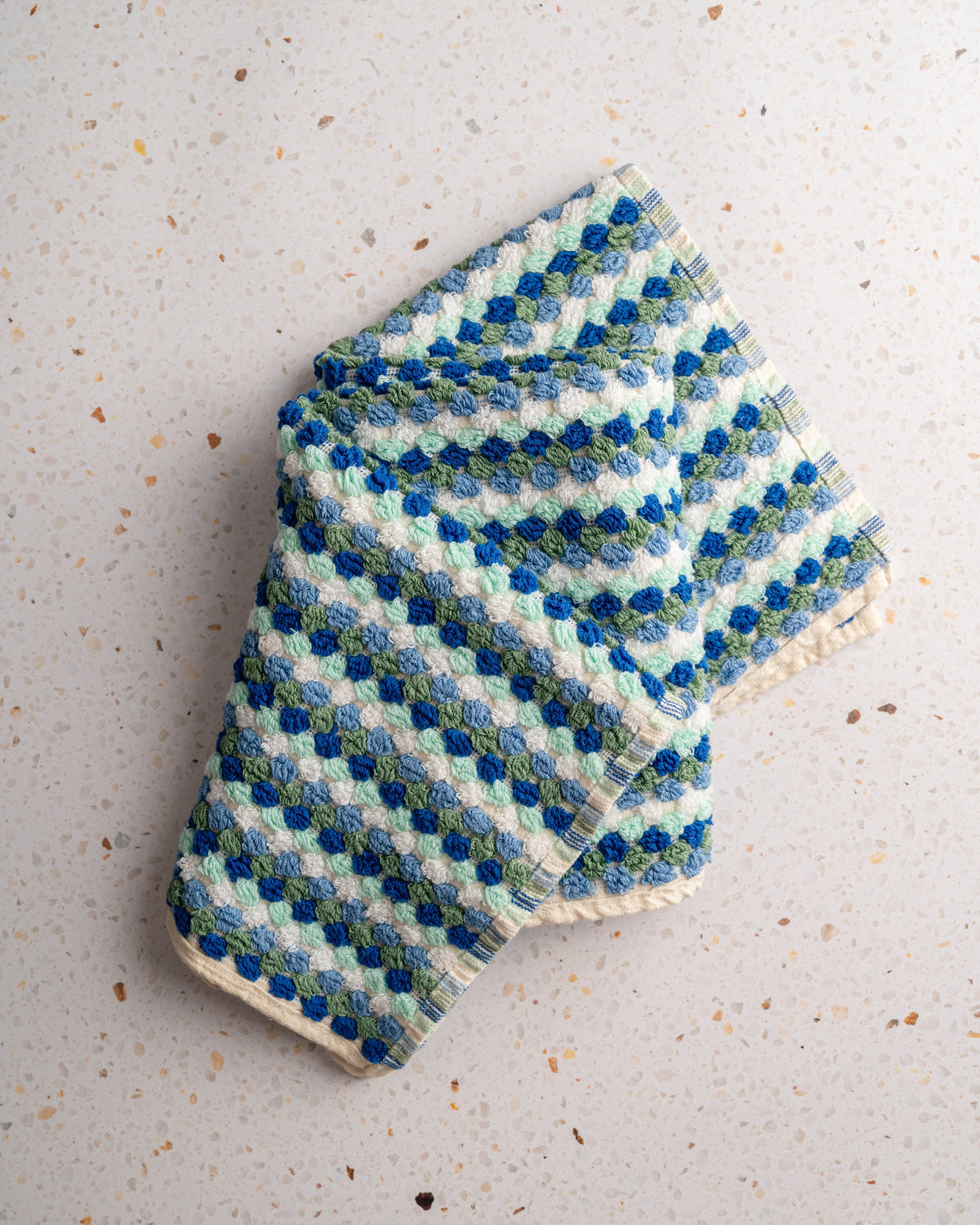 Checkered hand towel in blue and mint tones, no tassels, folded with hem visible.