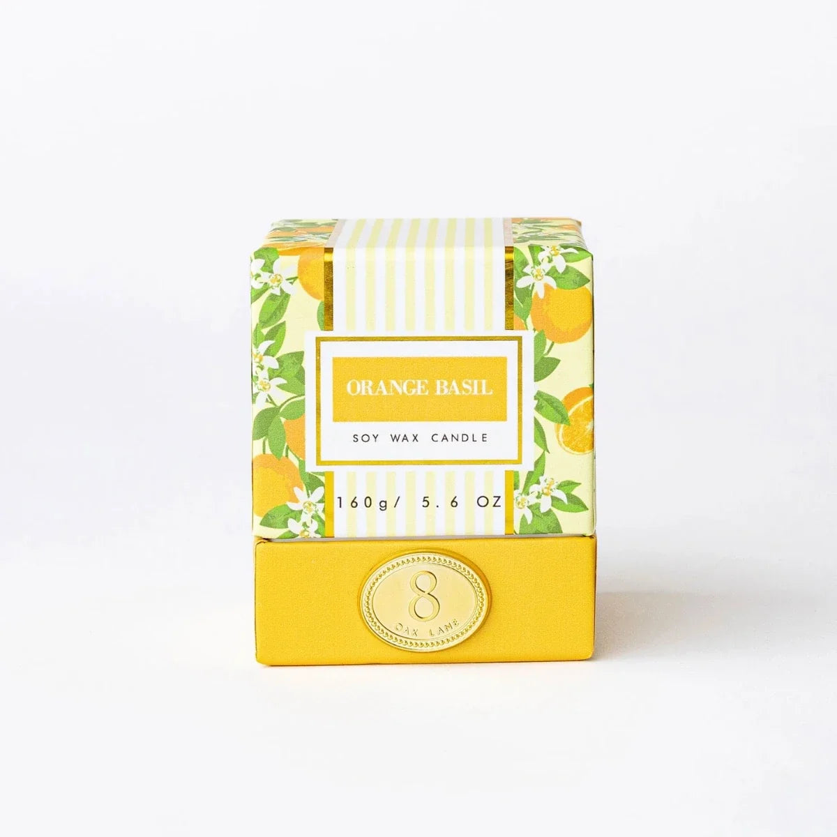 Boxed orange basil candle in patterned paper wrap with gold emblem