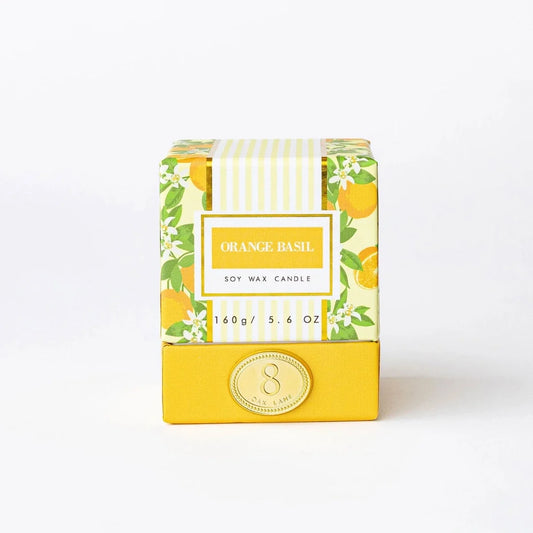 Boxed orange basil candle in patterned paper wrap with gold emblem