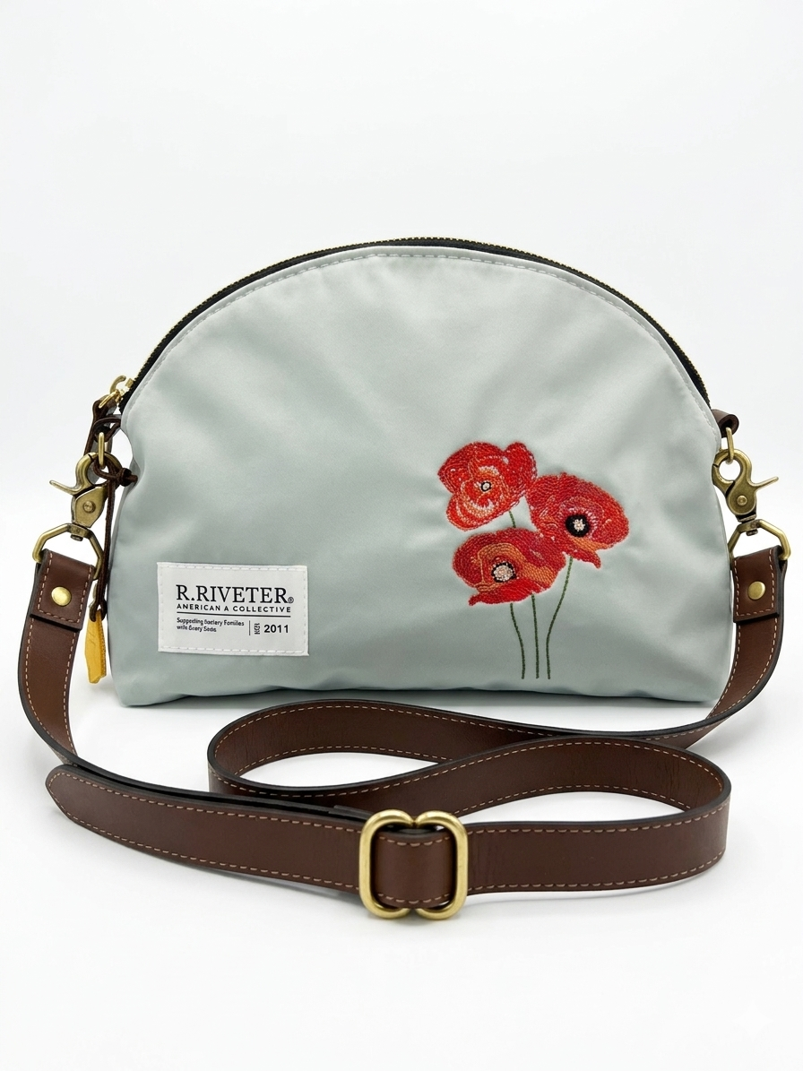 Light blue nylon crossbody bag with gold zipper, red embroidered poppies, brown leather strap and logo