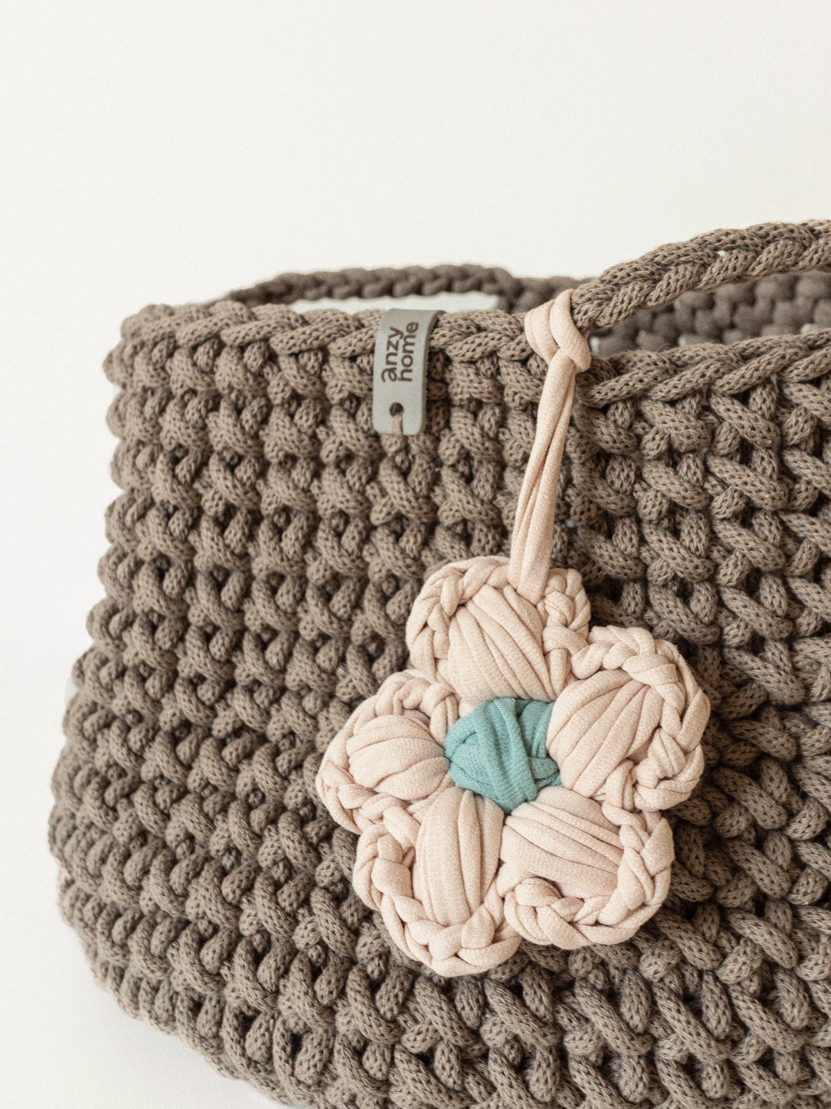 Close-up of gray crochet storage basket with beige braided flower detail