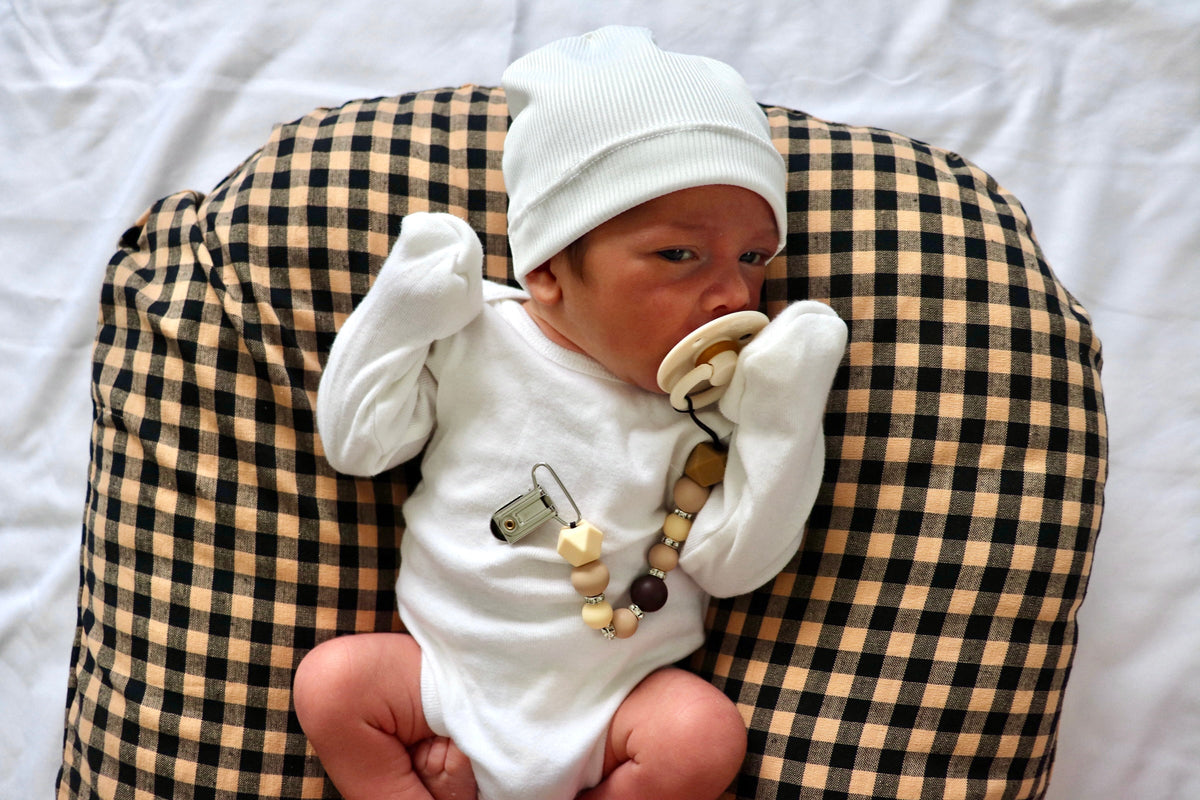 Brown and black gingham lounger cover shown beneath a seated baby