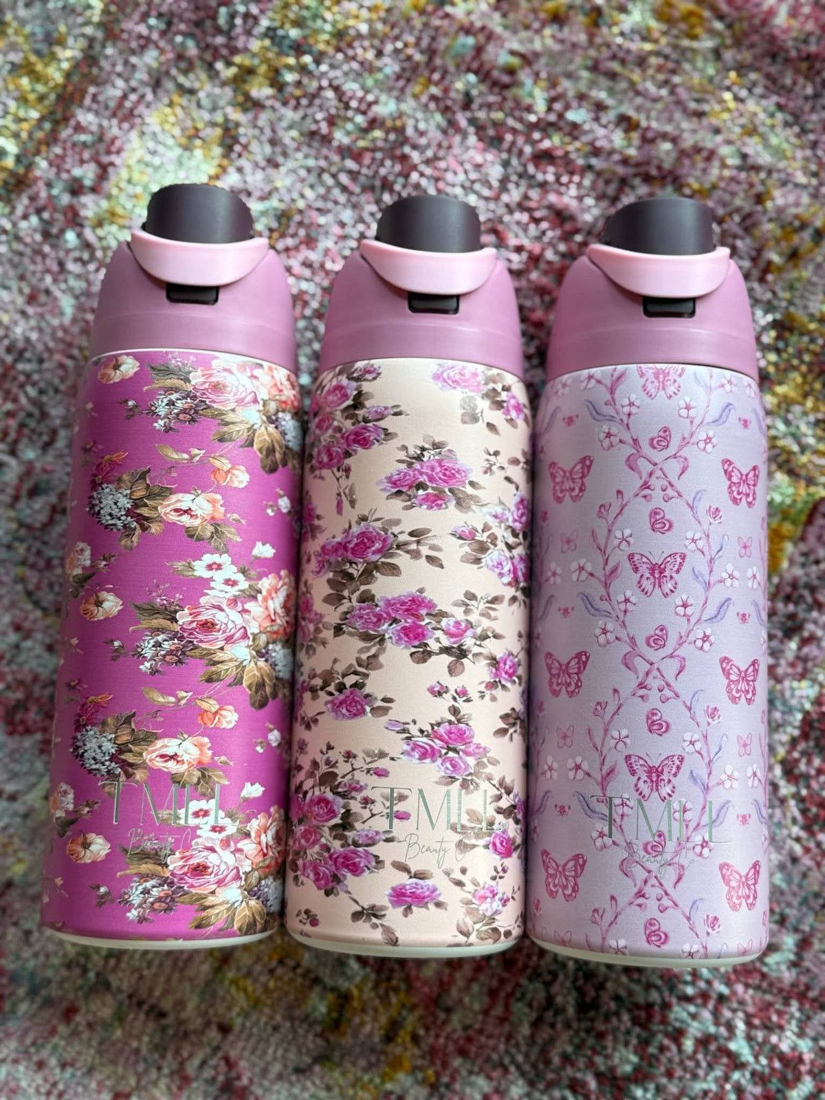 Three insulated bottles with black flip-top lids in pink, cream, and light pink