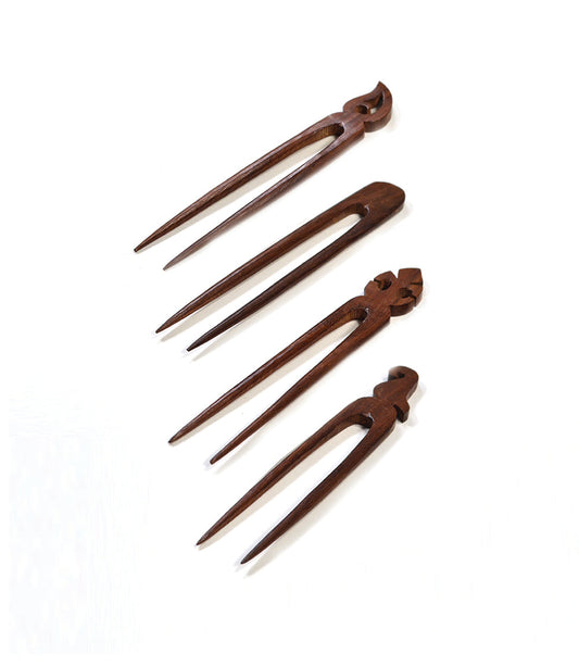 Four hand-carved wooden hair pins in dark brown with pointed prongs and carved ornamentation