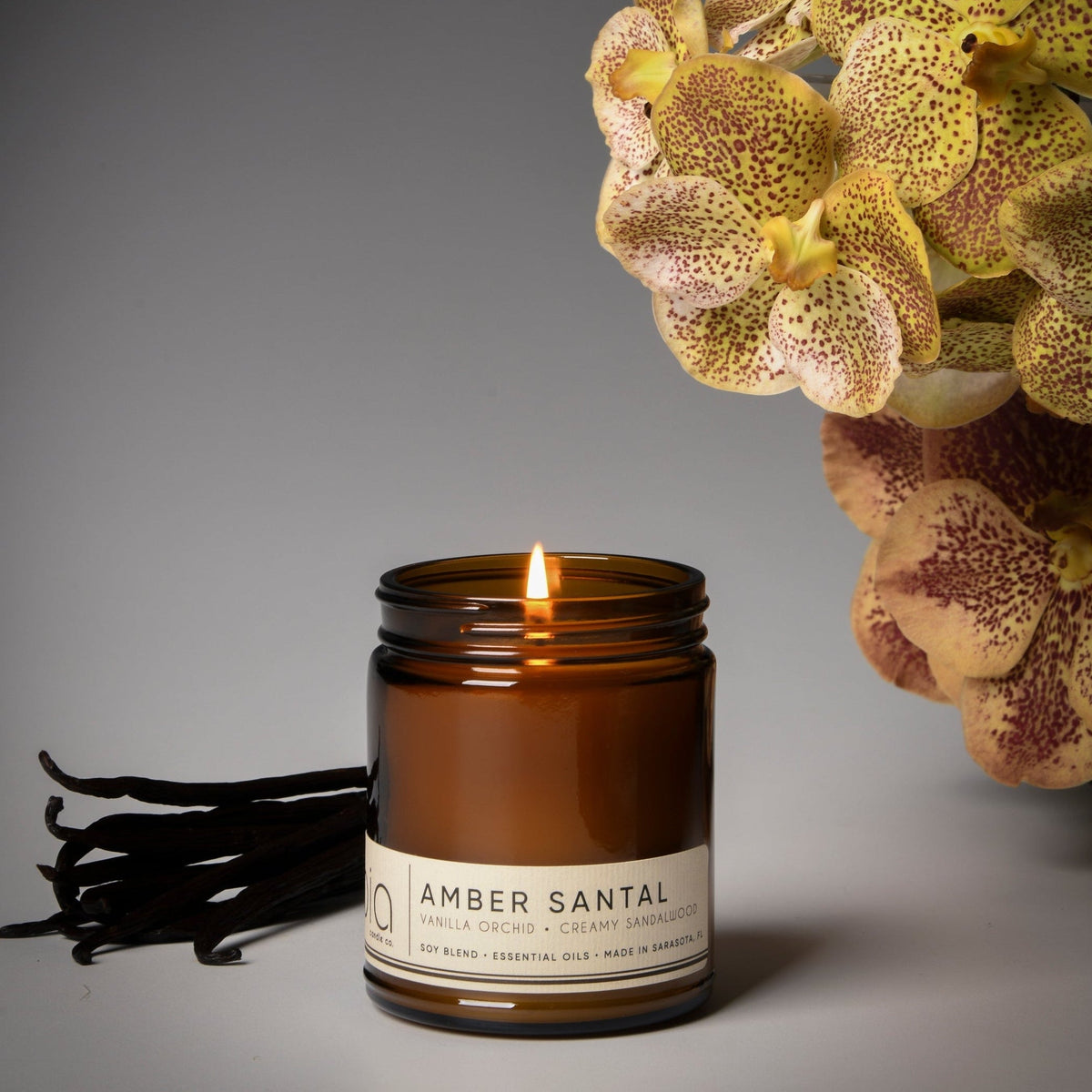 Amber candle jar with lit wick and Amber Santal label in amber glass