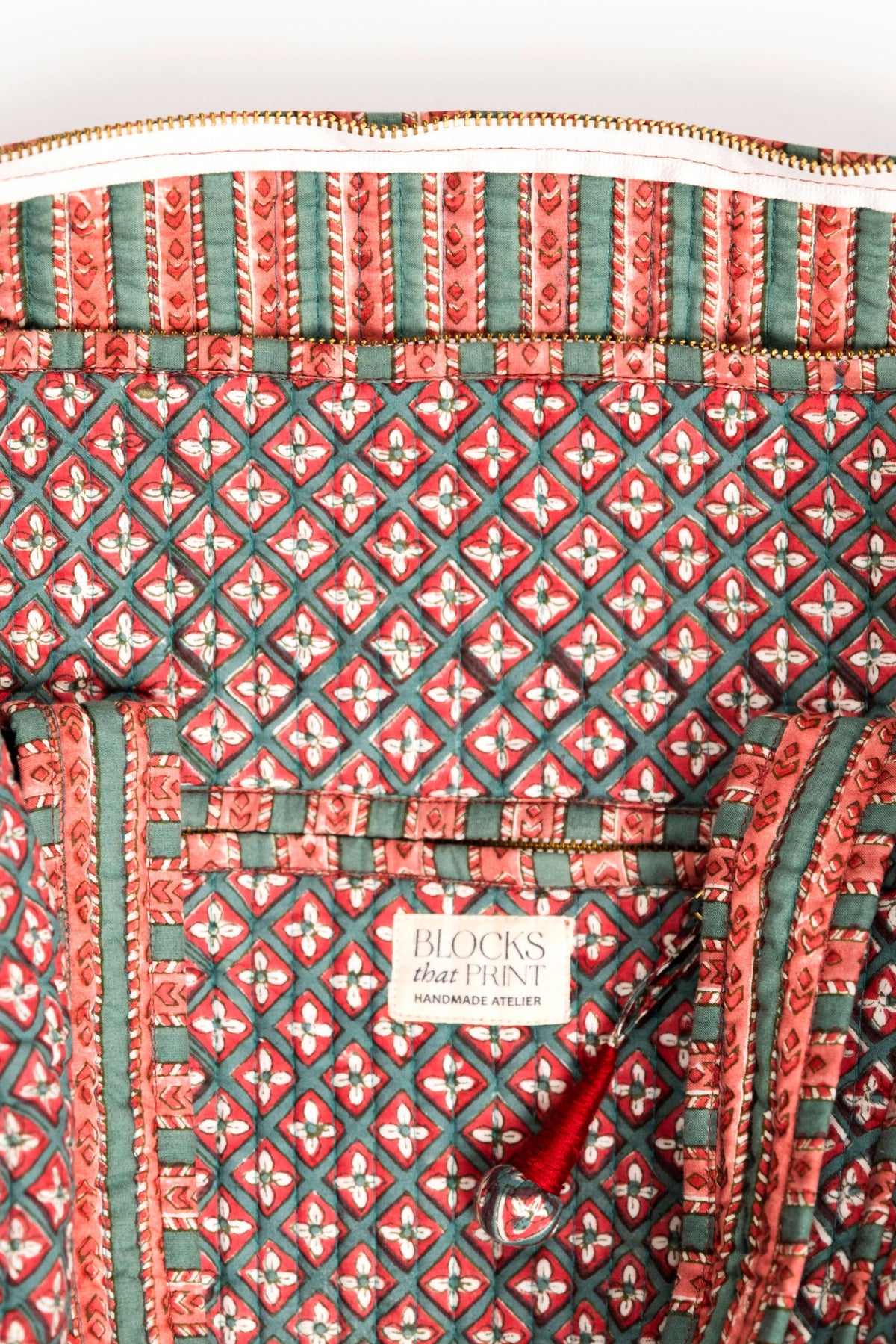 Interior panel of quilted duffle bag, red-and-green geometric print and striped trim