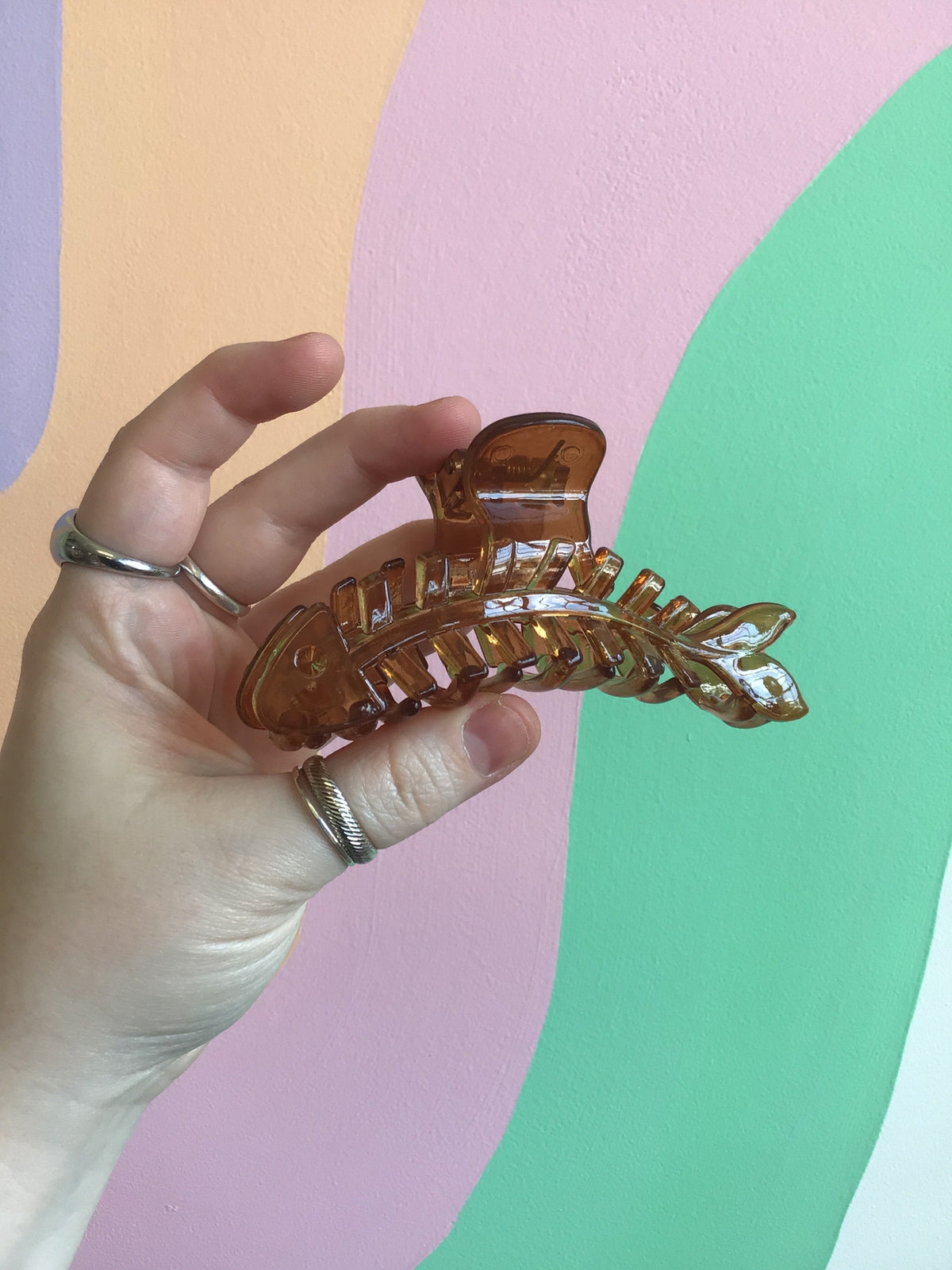 Brown fish-shaped hair claw with gold-toned embellishments and curved spine detail