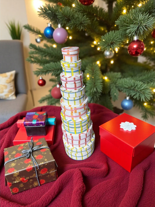 Stack of round handmade recycled paper gift boxes with colorful plaid bands, on a red table.