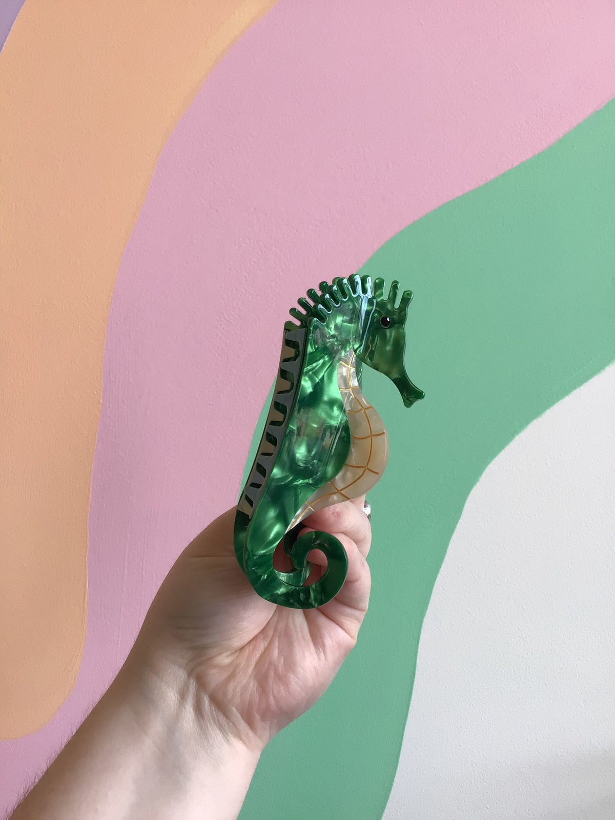 Green seahorse hair claw with black comb teeth and curled tail detail