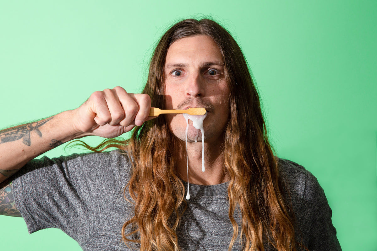 Canary toothpaste tablets being brushed by an adult with a wooden toothbrush