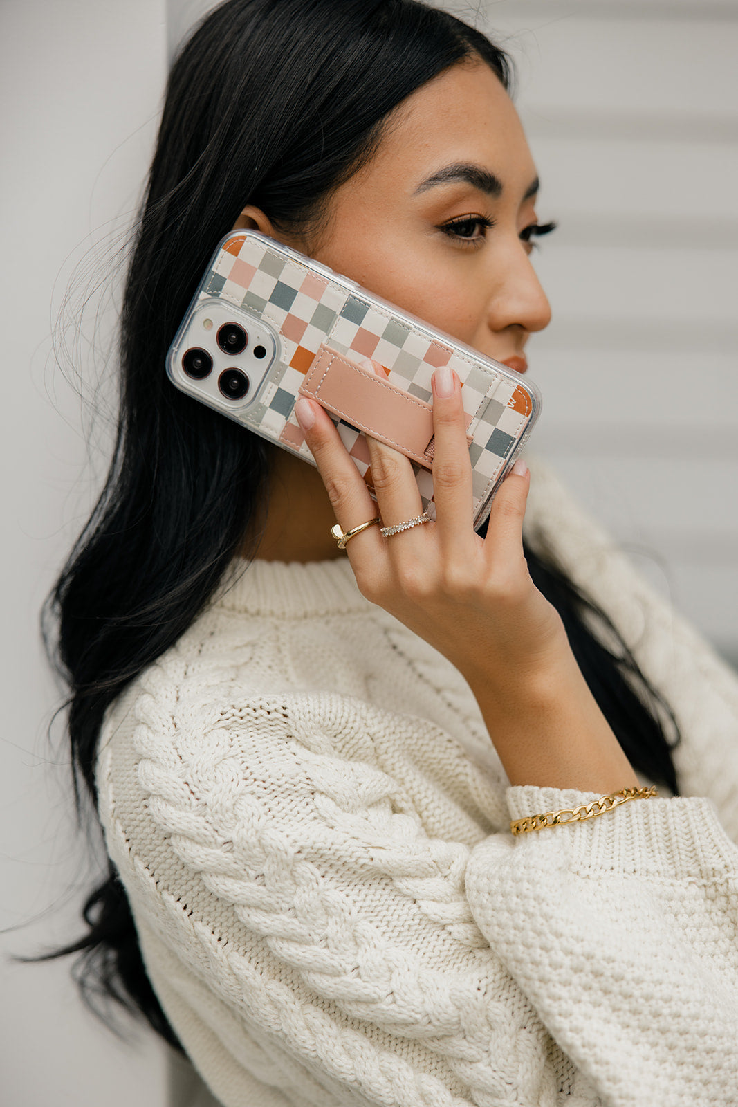 Checkerboard phone case with tan strap detail and camera lens openings