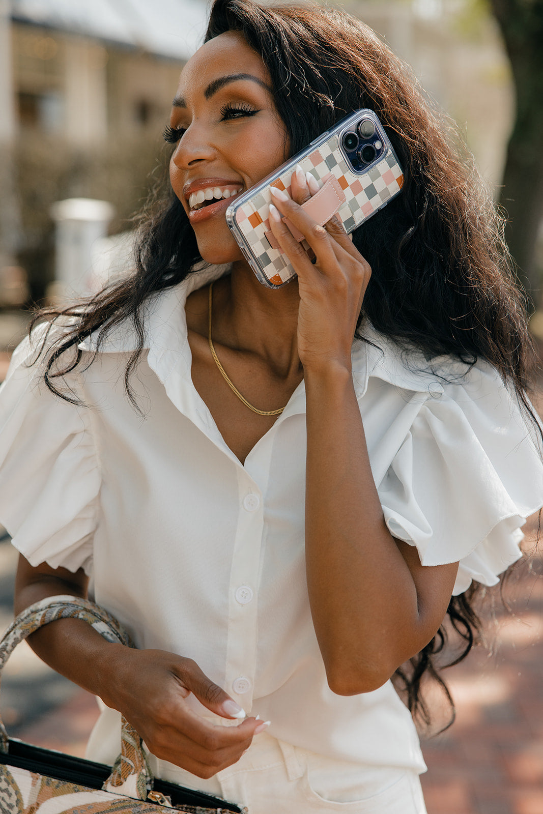 Checkerboard phone case with tan strap and camera lens openings