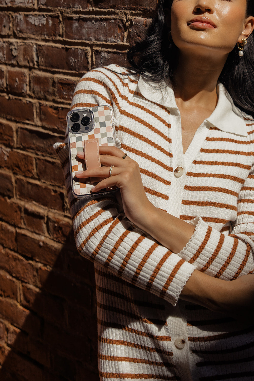 Phone case with multicolor checkerboard back and tan wrist strap