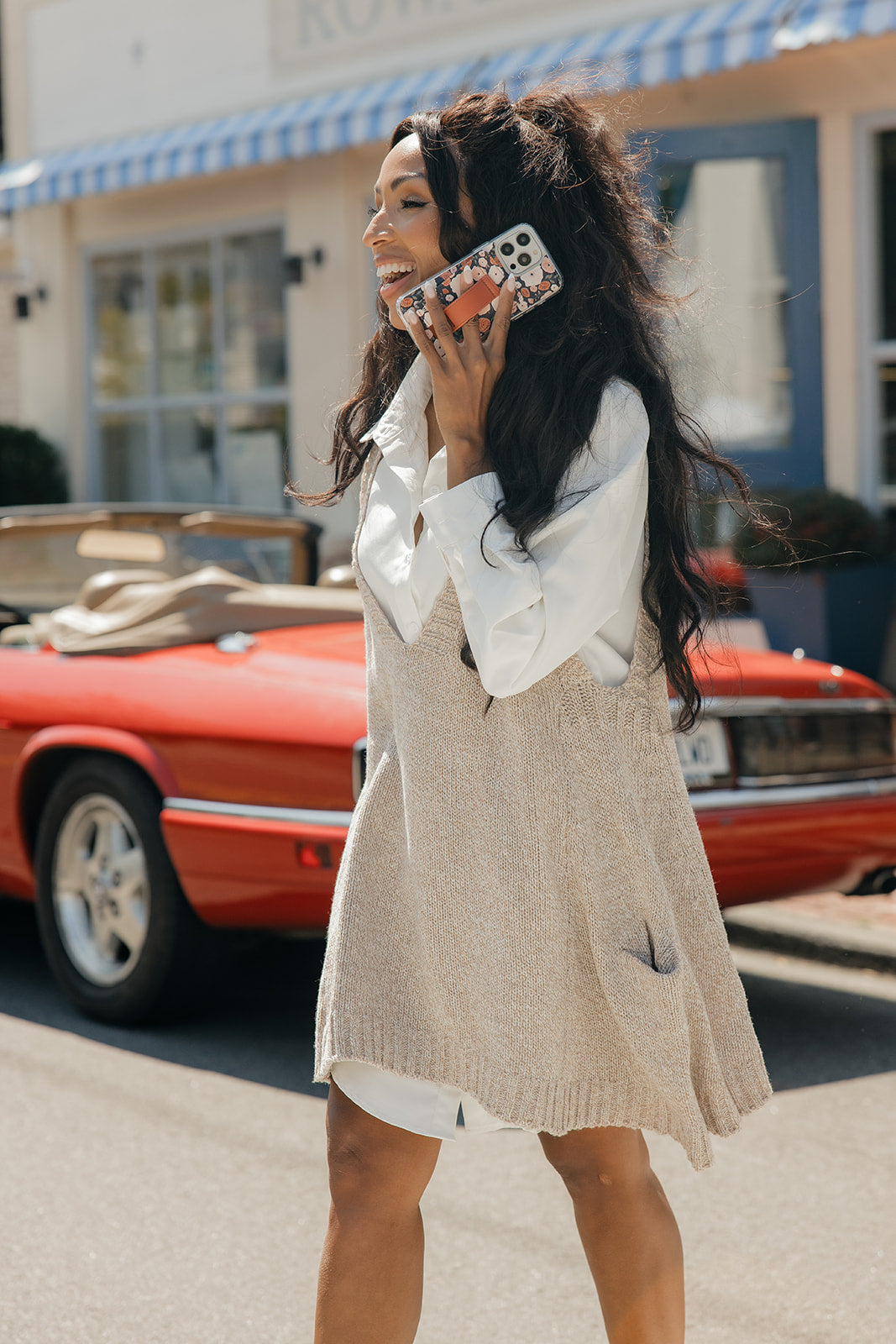 Floral phone case with brown strap, held to the cheek