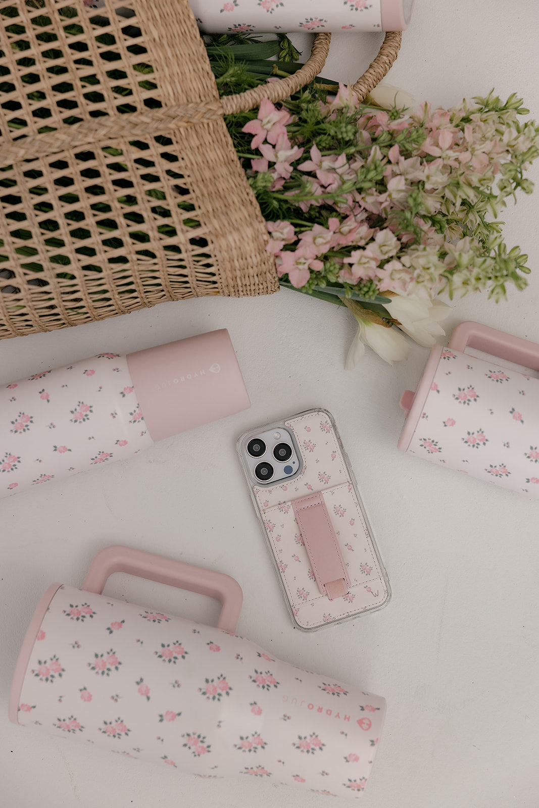 Wildrose pink floral phone case with vertical strap pocket, shown on tabletop