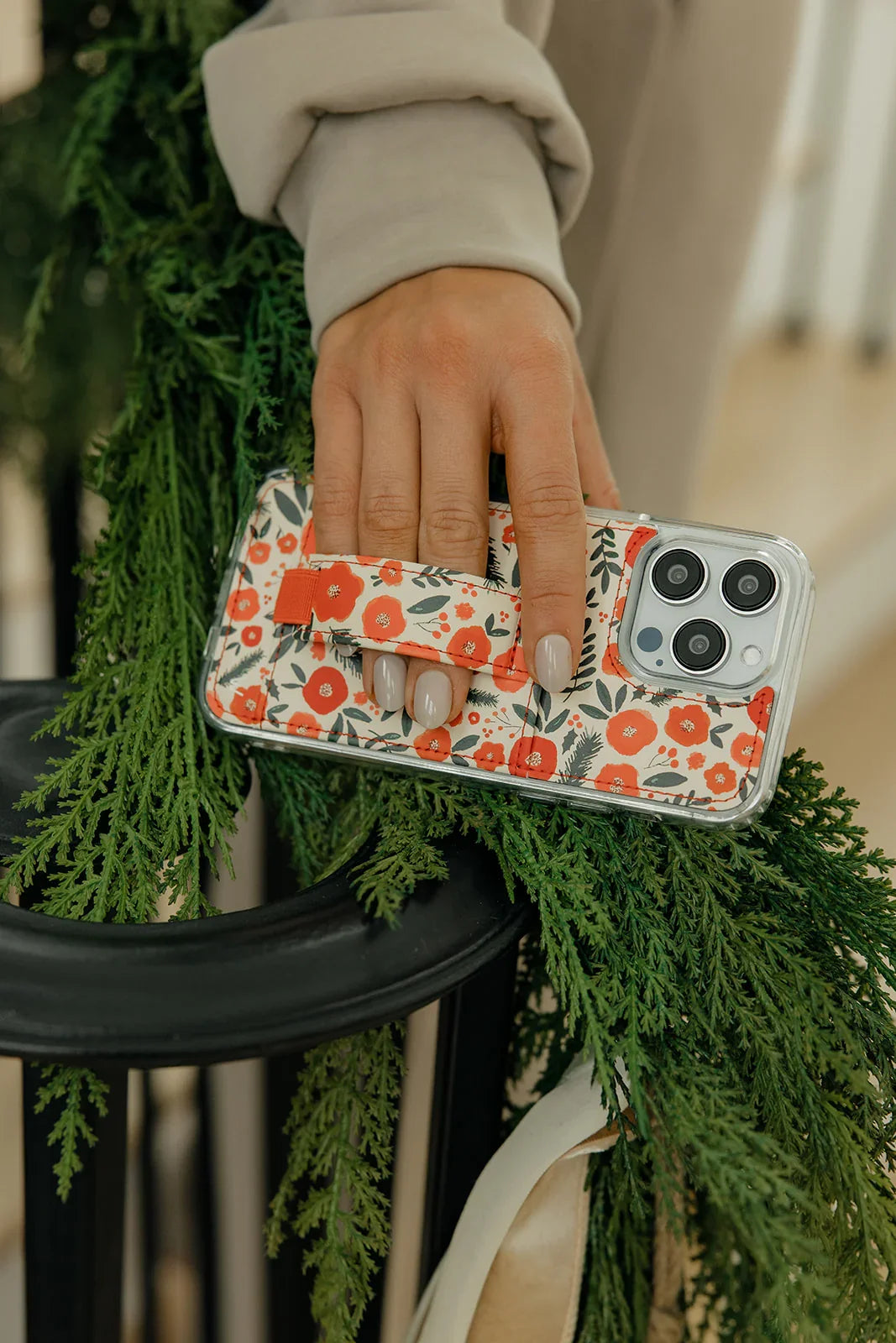 Red-and-white floral phone case with camera cutouts on a green branch