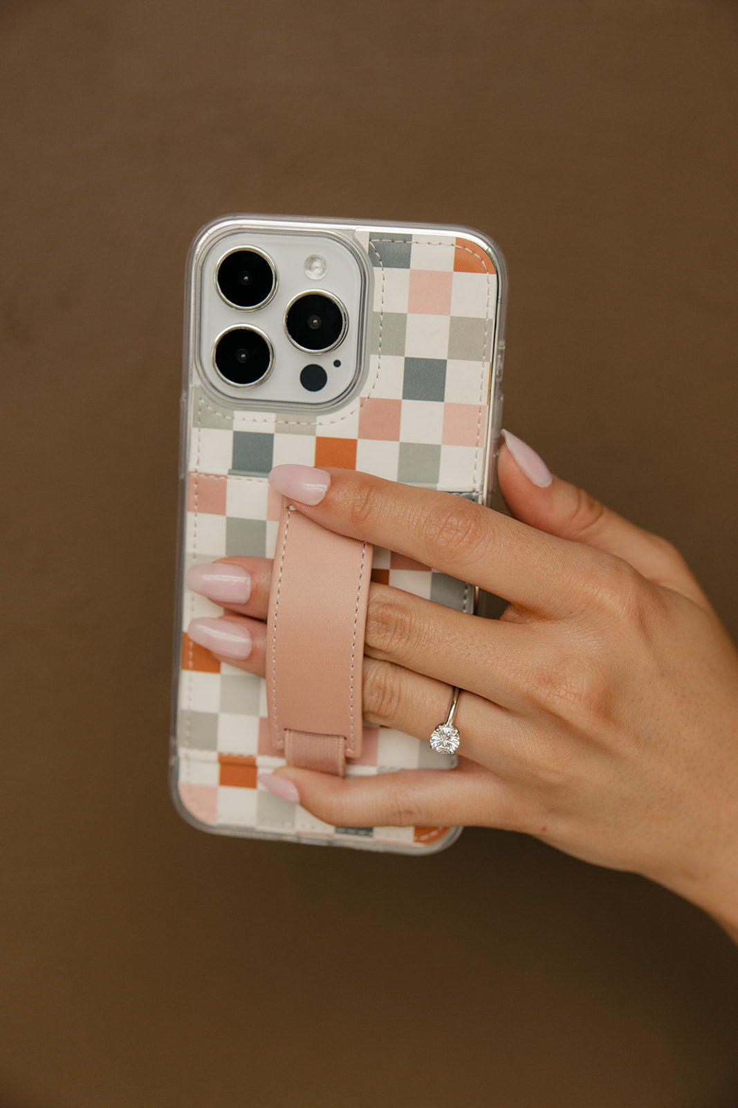 Clear phone case with multicolor checkerboard back and tan strap