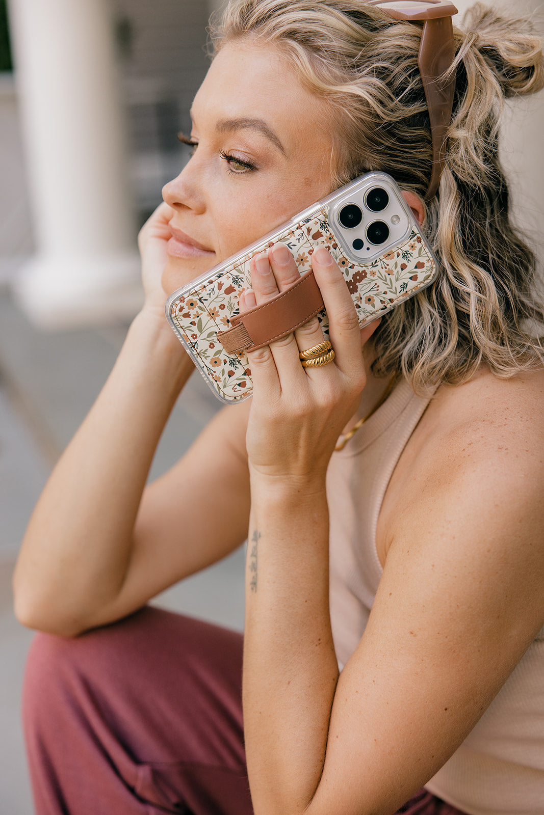 Floral phone case with brown strap pocket on smartphone during a call