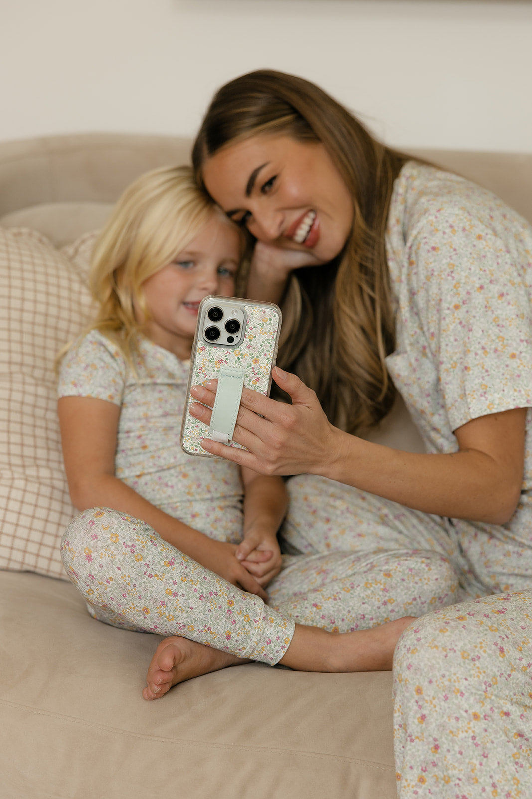 Petal Garden floral phone case with light blue strap held close by mother and child
