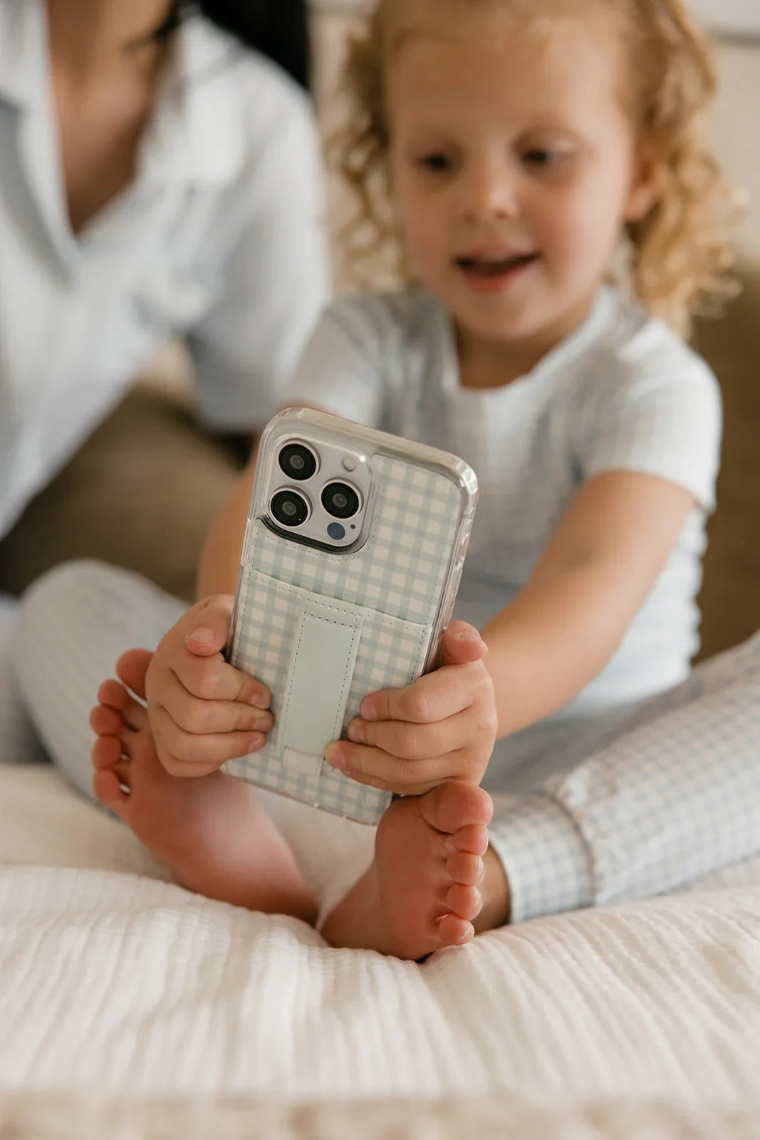 Light blue gingham phone case with strap, child holding the phone