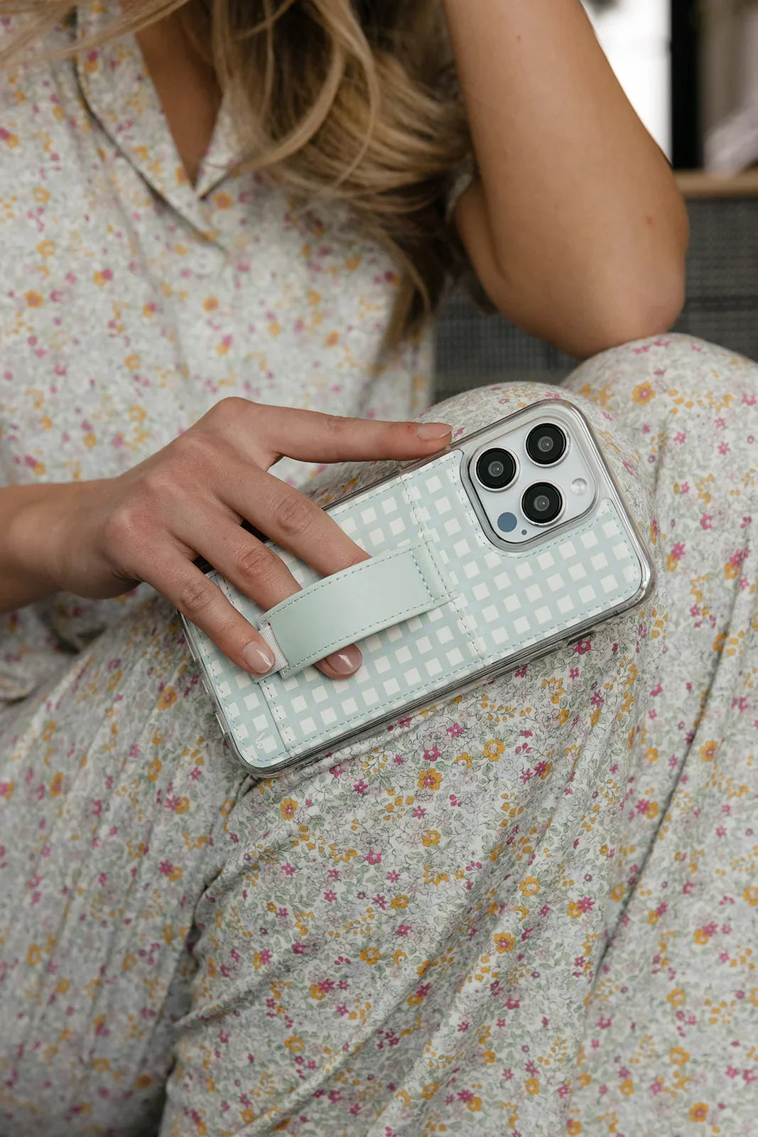 Light blue gingham phone case with card slot and strap, held on a floral dress