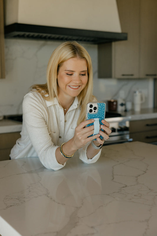 Teal phone case with white speckles and strap holder on a smartphone