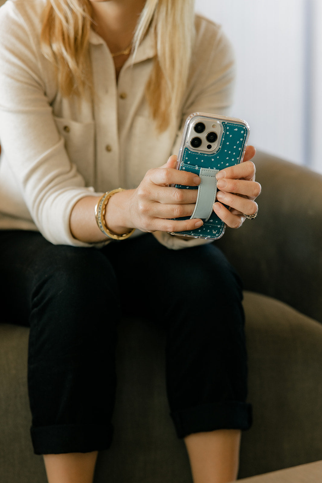 Teal phone case with white speckles and light blue strap holder in hand