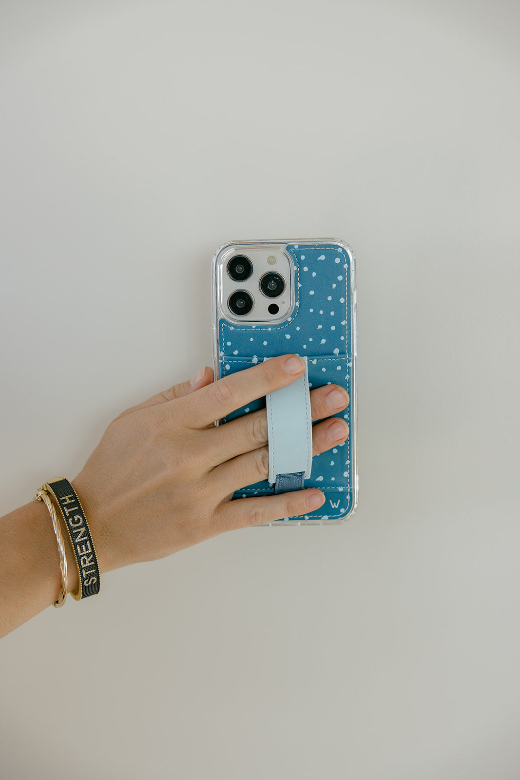 Teal phone case with white speckles and light blue strap holder, back view