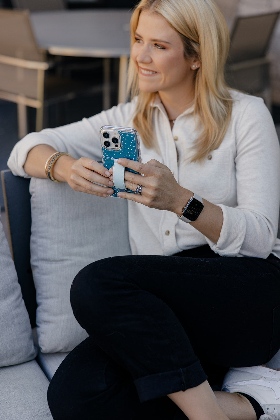 Teal speckled phone case with light blue strap holder while phone is held