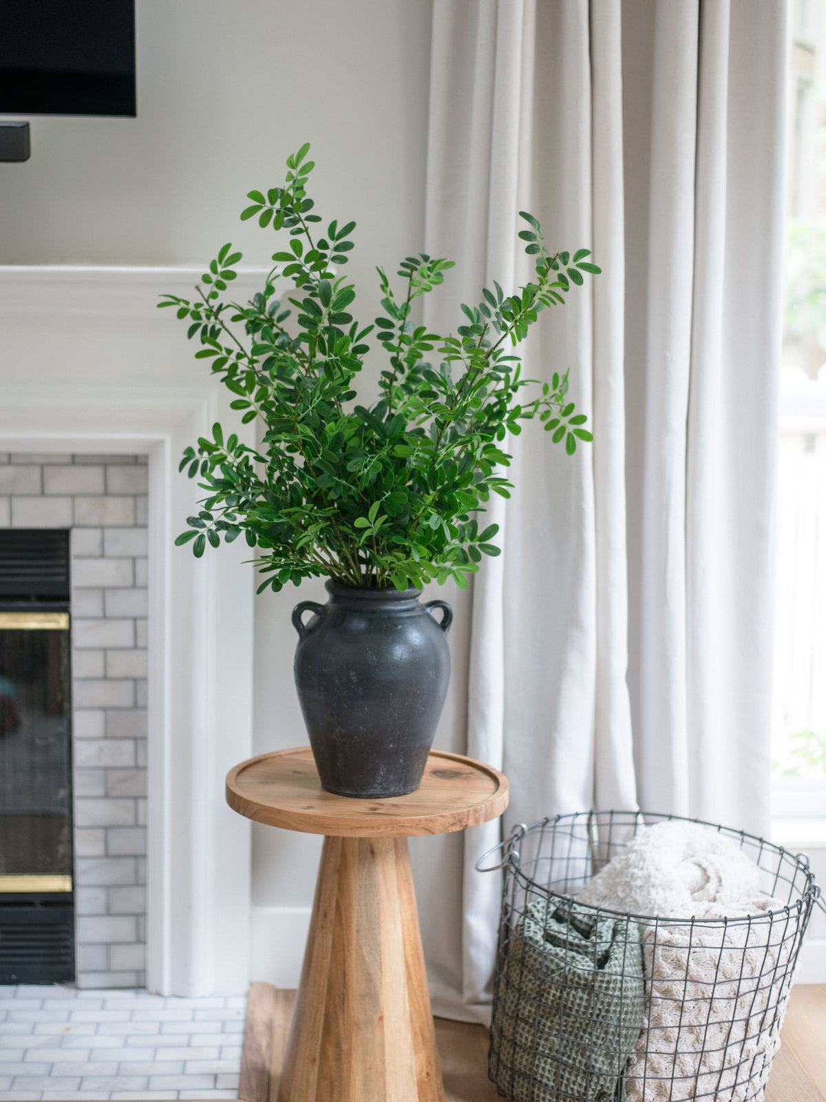 Artificial boxwood stems bundle of 4 in dark ceramic vase on tall wooden pedestal