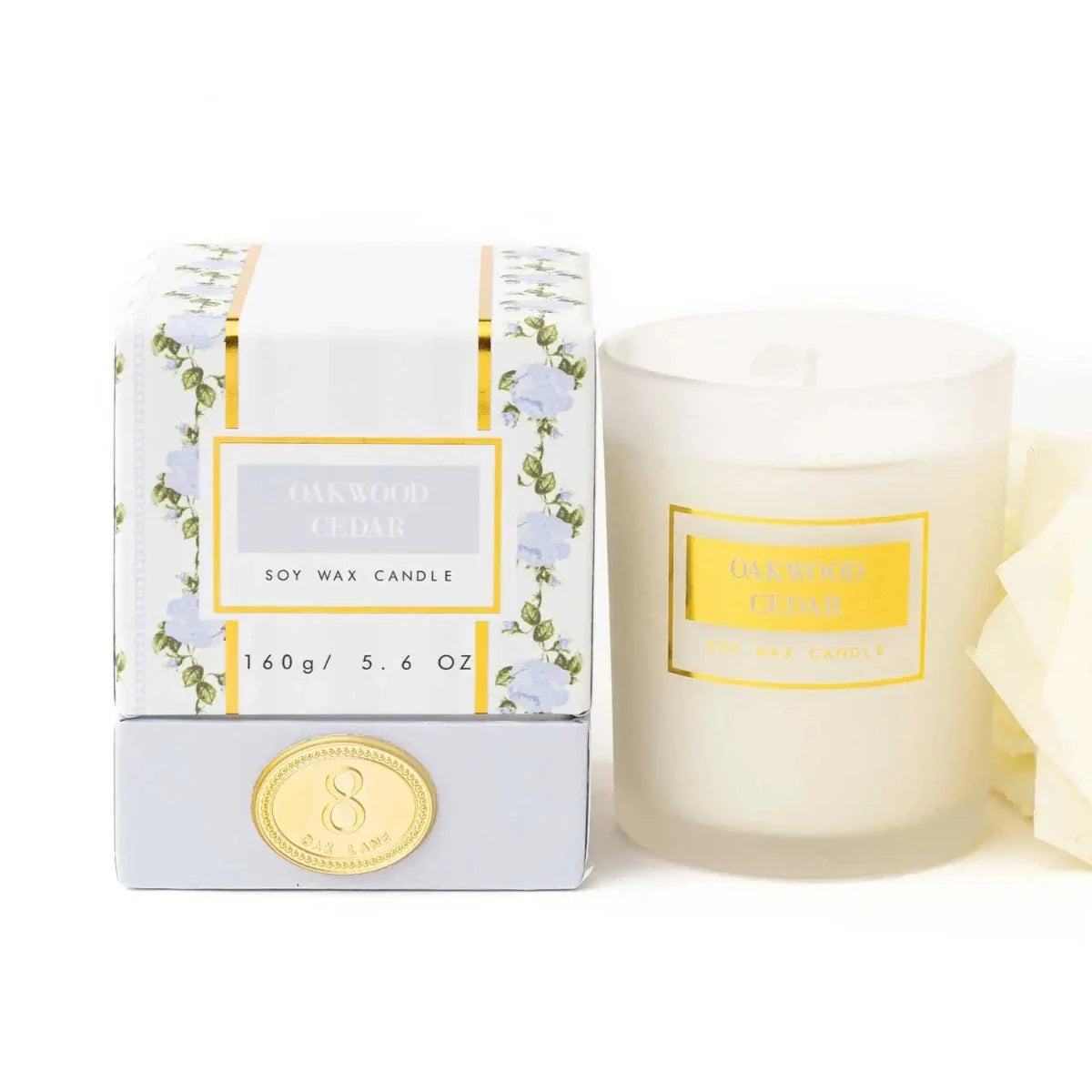 Boxed soy wax candle with Oakwood & Cedar label, gold seal, and floral wrap