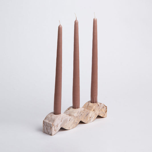 Wavy soapstone candelabra with three cream candles on a carved, veined base