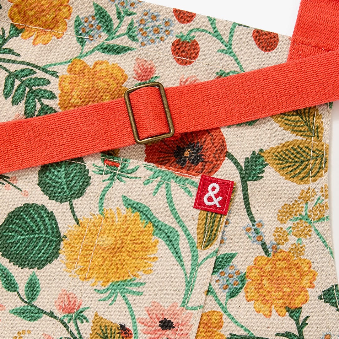 Orange neck strap with square buckle and small fabric tag on floral apron