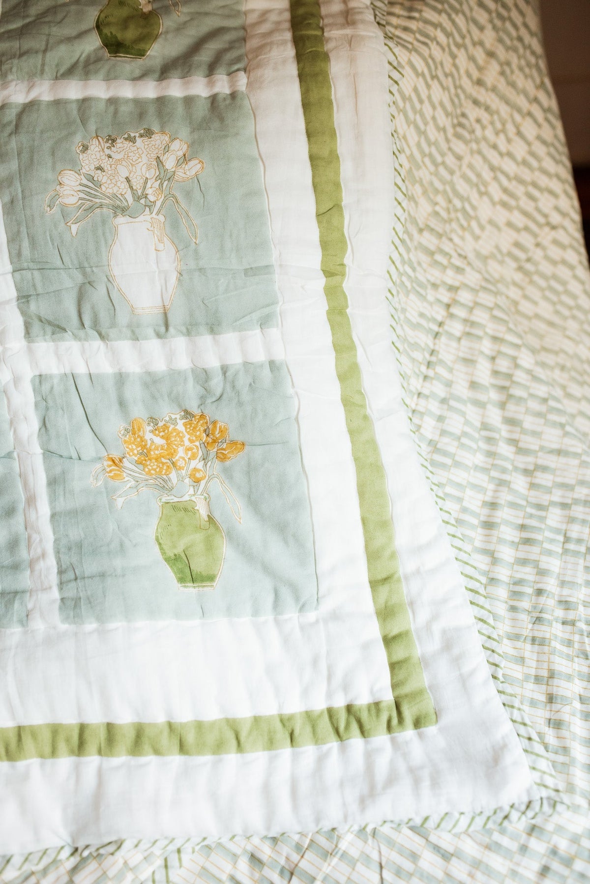 Quilt panel with floral motifs in pale green squares and vertical striped rows