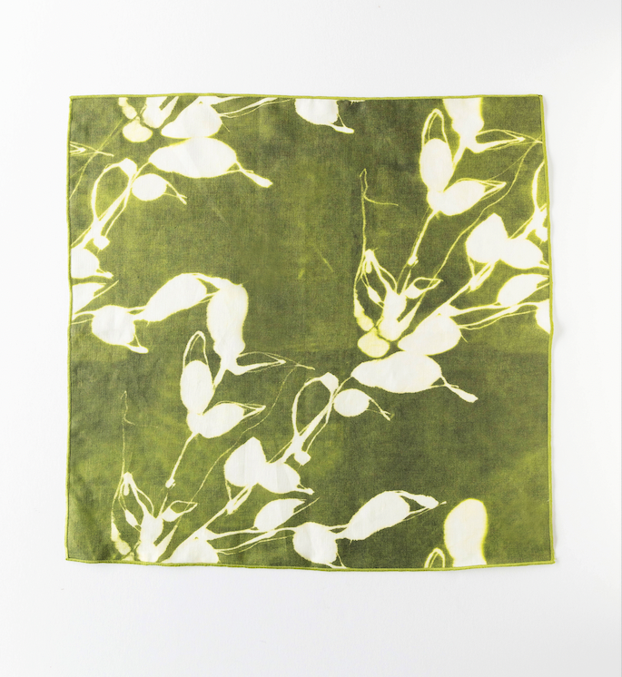 Flat olive dinner napkin featuring white flower and leaf pattern