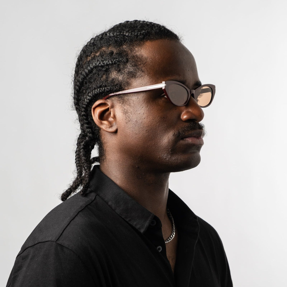 Model wearing burgundy cat-eye sunglasses with amber tinted lenses, profile view