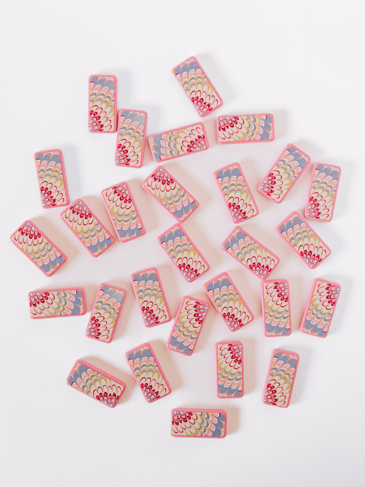 Scattered pink marbled domino tiles with yellow dot pips on tabletop