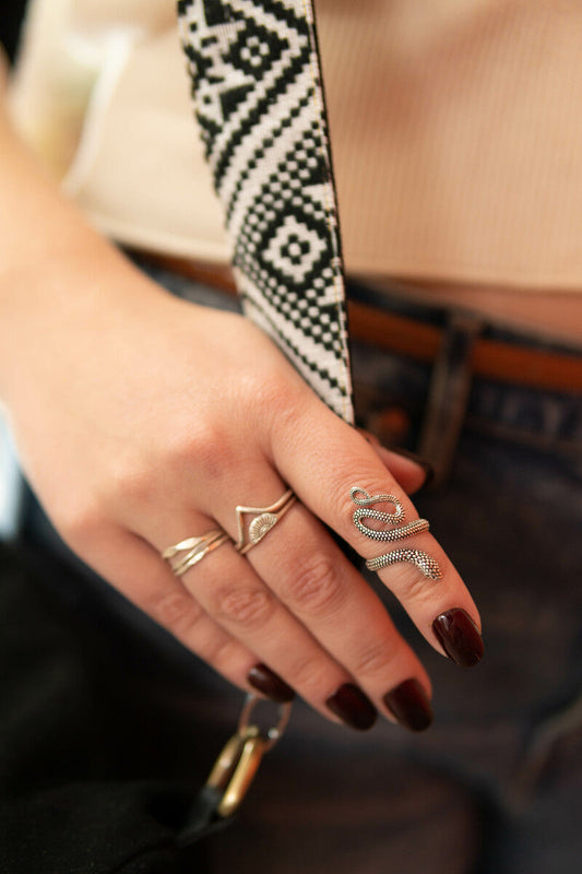 Snake-shaped ring with gold-tone scale texture on a hand, wide band