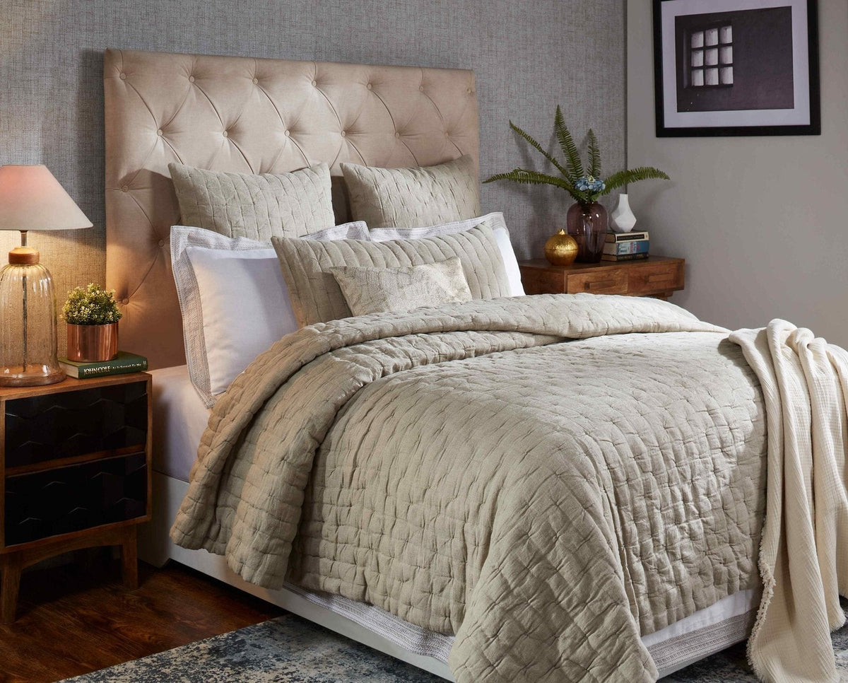 Light beige linen quilt on bed with pinched quilting and smooth outer edge.
