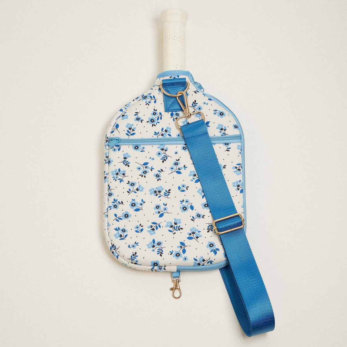 Blue floral paddle bag with adjustable strap draped across the front