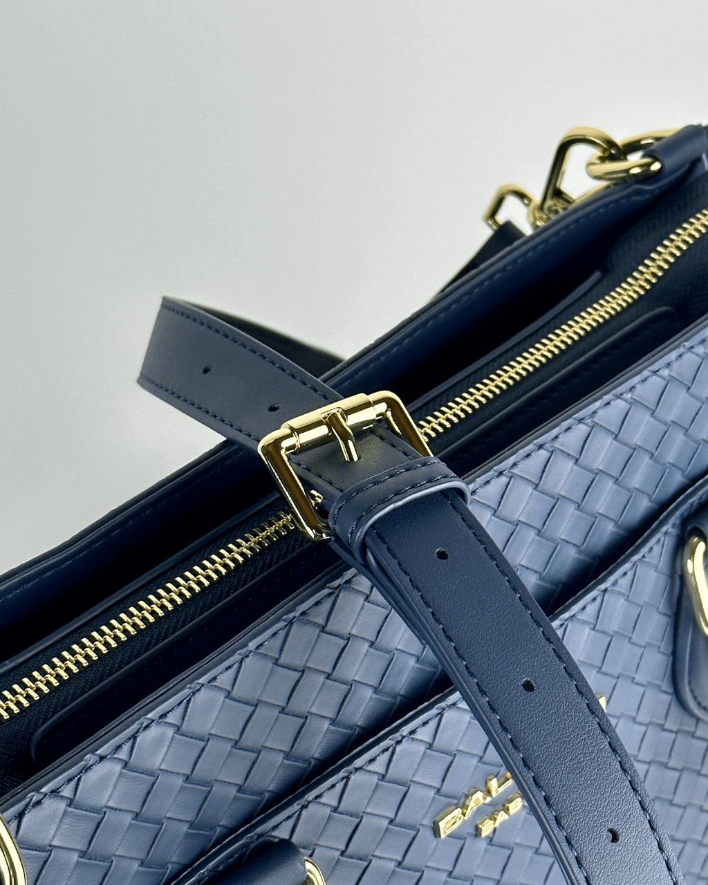 Close-up of the tote's adjustable handle buckle and gold-tone zipper