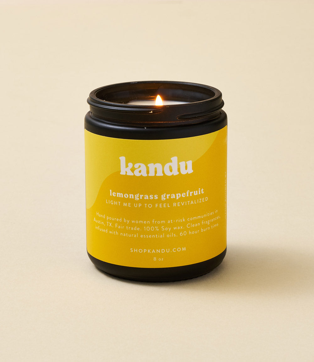 Lemongrass grapefruit candle in yellow kandu jar with lit wick and black lid